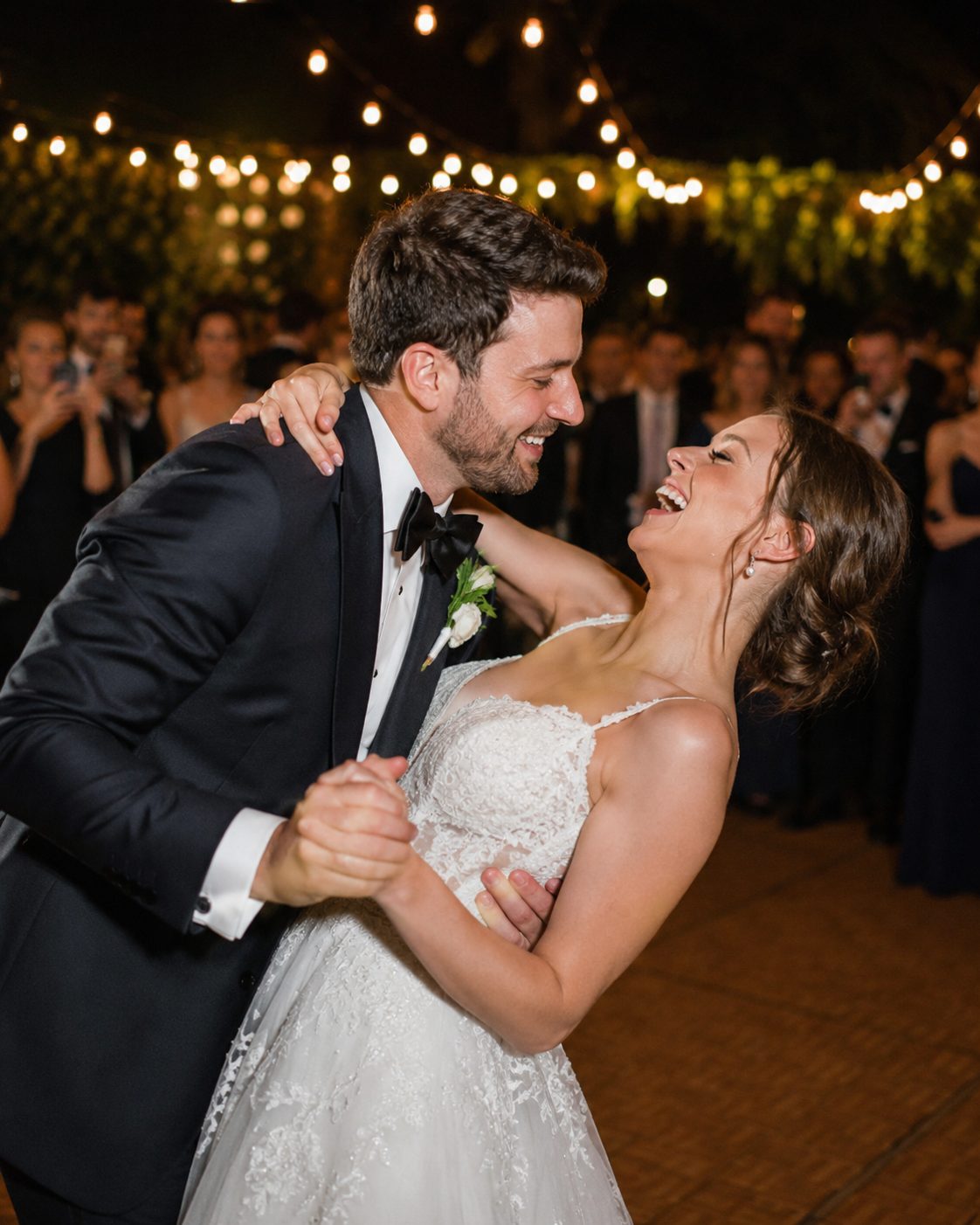 Bride and groom dancing under string lights
